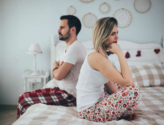 Couple assis dos à dos sur un lit